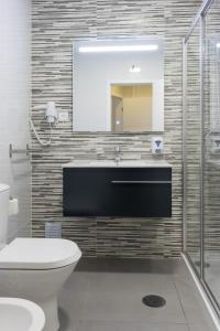 a bathroom with a toilet and a sink and a mirror at Riversuites Apartments in Coimbra