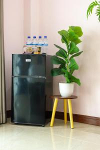 a black refrigerator sitting next to a table with a potted plant at Jindarin Villas จินดาริน คาเฟ่ in Ban Nong Sarai (1)