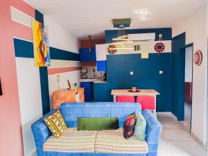 a living room with a blue couch and a kitchen at Mooksquare - DN SPOT in Douala