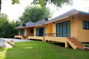 a yellow house with a lawn in front of it at Jindarin Villas จินดาริน คาเฟ่ in Ban Nong Sarai (1)
