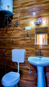 a bathroom with a blue toilet and a sink at Apple hills Resort in Jibhi