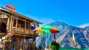 a building with a colorful umbrella in front of a mountain at Apple hills Resort in Jibhi
