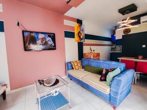a living room with a blue couch and a tv on the wall at Mooksquare - DN SPOT in Douala +14 photos