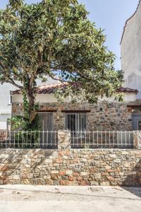 a stone wall with a tree in front of a building at The stone house in skiathos in Skiathos Town