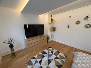 a living room with a flat screen tv on a white wall at Le Rossignol 1 er etage in Avranches