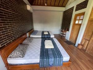 two beds in a room with a brick wall at Saka Homestay Boutique & Cafe in Borobudur