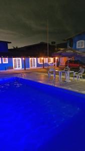 a swimming pool at night with chairs and an umbrella at Pousada Genesis Guaruja in Guarujá +24 photos