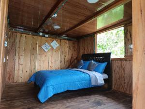 a bed in a room with a wooden wall at Finca El Encanto del Guejar in Lejanías