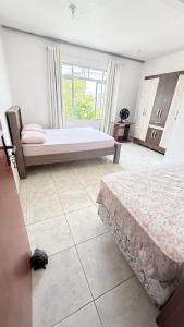 a bedroom with two beds and a large window at Pousada Altos dos Ingleses II in Florianópolis