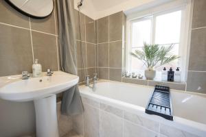 ein Bad mit einem Waschbecken, einer Badewanne und einem Fenster in der Unterkunft 4-Bedroom Central Canterbury Cottage in Kent + 41 Fotos