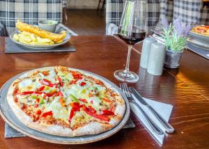 a pizza on a table with a glass of wine at Ogwen Bank Caravan And Lodge Park in Bethesda