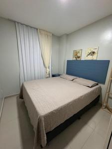 una camera da letto con un letto con testiera blu e una finestra di VGFUN Praia do Futuro Ap130 2 quartos 2 WCs 60m2-IMOB TEMPORADA a Fortaleza