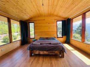 una camera da letto con un letto in una stanza con finestre di Heshkili huts and cabins Svaneti a Keshkili