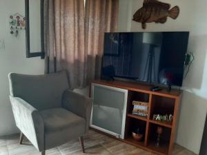 sala de estar con silla y TV de pantalla plana en Refúgio de Paz, en Capão da Canoa