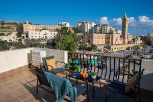 balcone con tavolo, sedie e vista sulla città di Seafront 4-Bed Townhouse with Breathtaking Views a Iż-Żlielaq