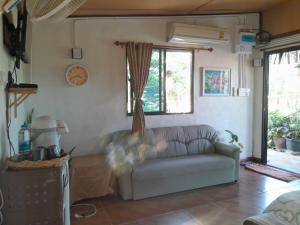 a living room with a couch and a window at Sukanya Garden and Home in Ban Lat Ya