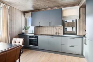 eine Küche mit weißen Schränken und einem Tisch in der Unterkunft Hafjell Front 8pers Ski InOut in Hunder