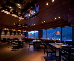 a restaurant with tables and chairs and large windows at Furuyu Onsen Oncri in Saga