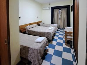 a hotel room with three beds and a checkered floor at Hotel La Giralda in Buenos Aires