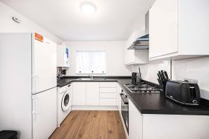 a kitchen with white cabinets and a black counter top at Stylish London Flat - 5 Sleeper in Ilford +20 photos