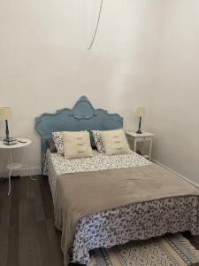 a bedroom with a bed with a blue headboard and two tables at Casa Brisa Abades in Abades