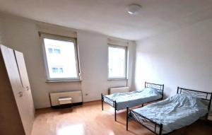 two beds in a room with two windows at Monteurzimmer fitter room Apartment Bruchsal Heilbronn Bretten in Oberderdingen