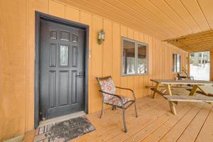 a porch with a black door and a table and a bench at Less Than 1 Mi to Nubs Nob Ski Cabin with Sauna and Deck! in Harbor Springs