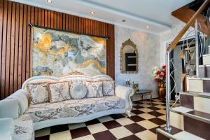 un salon avec un canapé et une grande peinture murale dans l'établissement Luxurious Villa with Lush Garden and Huge Terrace near Herastrau Park, à Bucarest