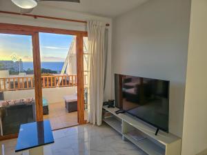 a living room with a flat screen tv and a balcony at Aqua Sun Los Geranios by HelloApartments in Adeje