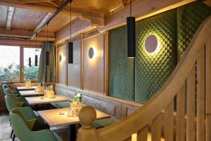 a restaurant with wooden tables and green walls at Hotel Montafon Moments in Sankt Gallenkirch