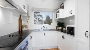a white kitchen with a sink and a window at Casa Blu in Culburra Beach