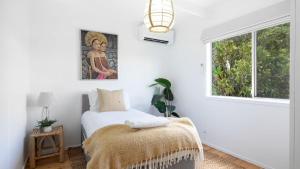 a white bedroom with a bed and a window at Casa Blu in Culburra Beach