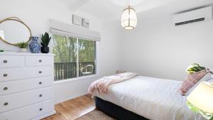 a bedroom with a bed and a dresser and a window at Casa Blu in Culburra Beach +20 photos