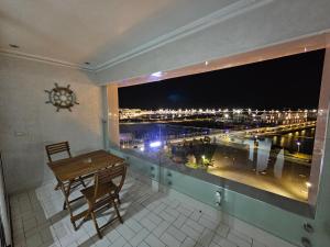 a balcony with a table and a view of a city at Panoramic Sea View Apartment 1 Min Walk to Beach in Tangier