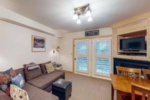 a living room with a couch and a tv and a table at Viking Lodge B218 in Telluride