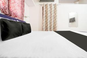 a bedroom with a white bed with a black pillow on it at Hotel O CROWN in Nagpur