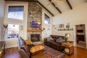 a living room with two leather couches and a stone fireplace at The Tee House in Beech Mountain +31 photos