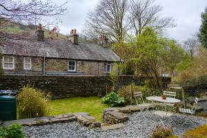 a stone cottage with a table and chairs in front of it at Fellfoot Cottage in the Lake District in Staveley