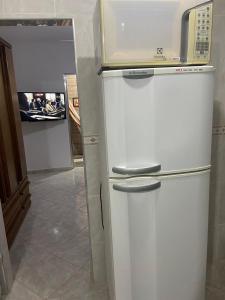 a white refrigerator with a microwave on top of it at Edifício Bandeirantes in Praia Grande
