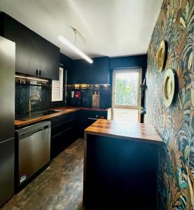 a kitchen with black cabinets and a wooden counter top at La Galerie - appartement entier -75 m2 in Noisy-le-Grand