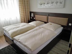 2 łóżka z białą pościelą i poduszkami w sypialni w obiekcie Hotel Alfa w mieście Neu-Isenburg