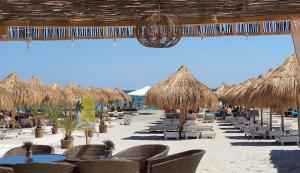a beach with tables and chairs and straw umbrellas at AlyStar apartament in Mamaia Sat/Năvodari
