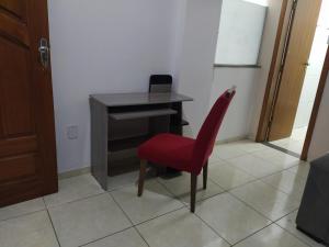 a red chair sitting in front of a desk at Apartment 104 charmoso in Vitória da Conquista