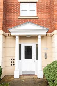a white door on a brick house at A spacious 2 bedroom apartment in Littleover, Derby! in Derby