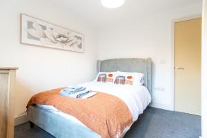a bedroom with a bed with an orange blanket at A spacious 2 bedroom apartment in Littleover, Derby! in Derby
