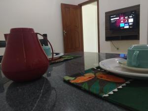un jarrón rojo sentado en una mesa con un plato en Apartment 203 Charming, en Vitória da Conquista 3 fotos más