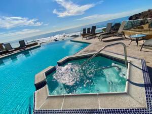 a swimming pool with chairs and the ocean in the background at Rosarito Beach and pool access apartment 2bd 2b in Popotla