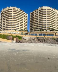 two tall buildings next to a beach with the ocean at Rosarito Beach and pool access apartment 2bd 2b in Popotla