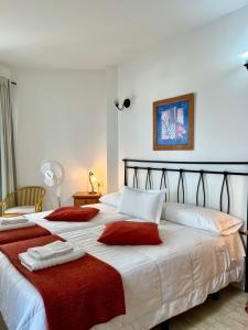 two beds in a bedroom with red blankets and towels at Apartamentos Edalmar in Frontera