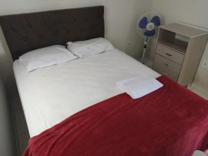 1 cama con sábanas blancas y manta roja en 301 Apartamento Charmoso, en Vitória da Conquista